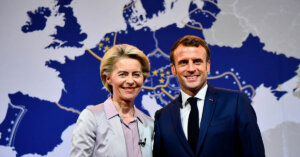 Macron et Van der Leyen tout sourire et en fond une carte de l'Europe au couleur du drapeau de l'Union européenne