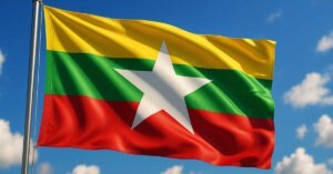 Drapeau du Myanmar flottant au vent sous un ciel bleu, symbole national représentant l’unité et la résistance du peuple birman face à la junte militaire.